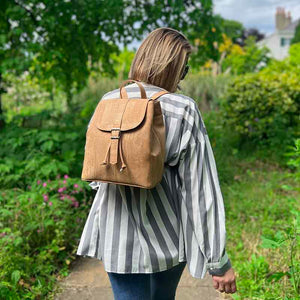Model carrying a natural cork drawstring backpack with folding top