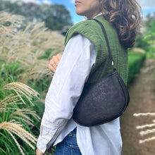 Load image into Gallery viewer, Model carrying the black cork half-moon bag on her shoulder