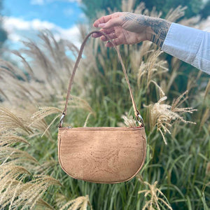 Hand holding a natural cork half-moon shoulder bag