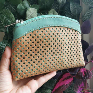 Hand holding the large cork purse with polka dot laser cuts in natural and turquoise-tinted cork