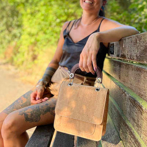 Model holding a mini cork top handle handbag