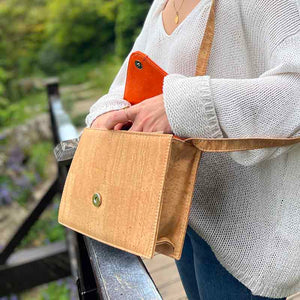 Model opens a natural, red and orange cork crossbody bag