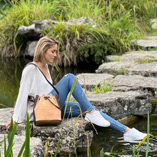 Load image into Gallery viewer, Model carrying a natural and brown tinted cork fabric bucket bag with drawstring